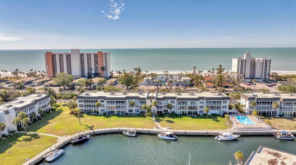 An aerial view shows a waterfront condominium complex with a pool and boat docks — 4350 CHATHAM DRIVE UNIT 106, LONGBOAT KEY, FL