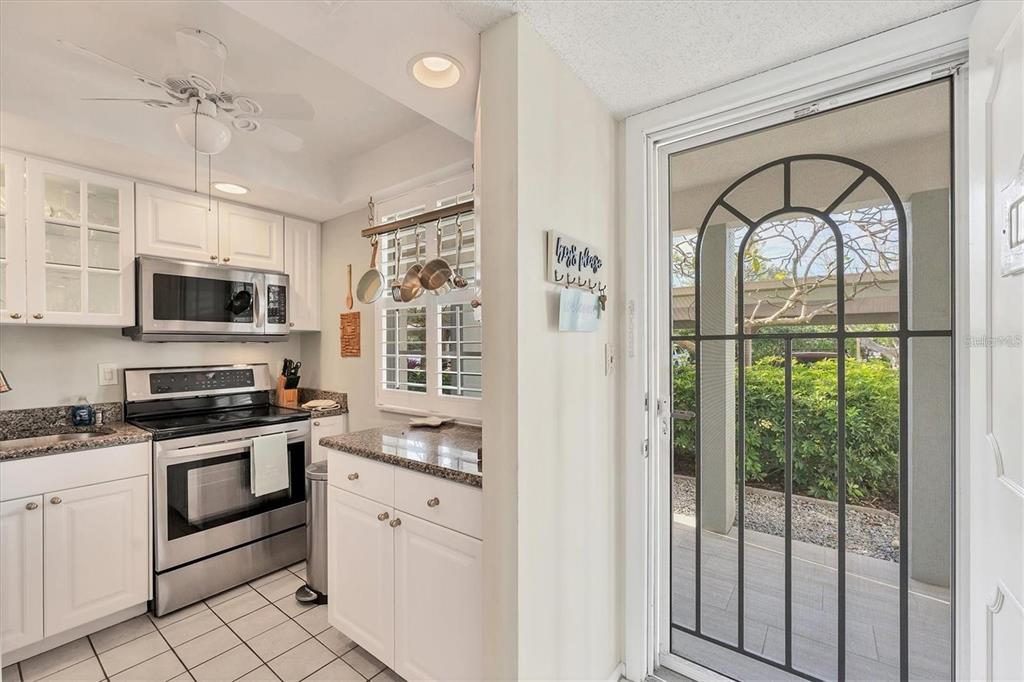 A kitchen with white cabinets, stainless steel appliances, and a glass door leading to a patio — 4350 CHATHAM DRIVE UNIT 106, LONGBOAT KEY, FL