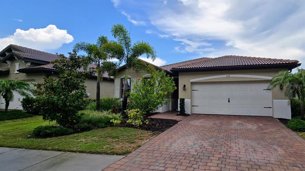 A single-story house with a tiled roof, white garage door, and a brick paver driveway — 233 VINADIO BOULEVARD, NOKOMIS, FL
