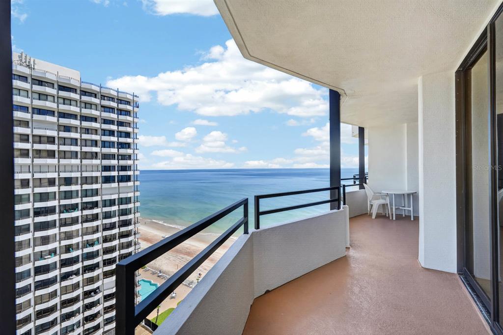 A balcony with a black railing overlooks the ocean and a neighboring high-rise building — 2828 N ATLANTIC AVENUE UNIT 1505, DAYTONA BEACH, FL