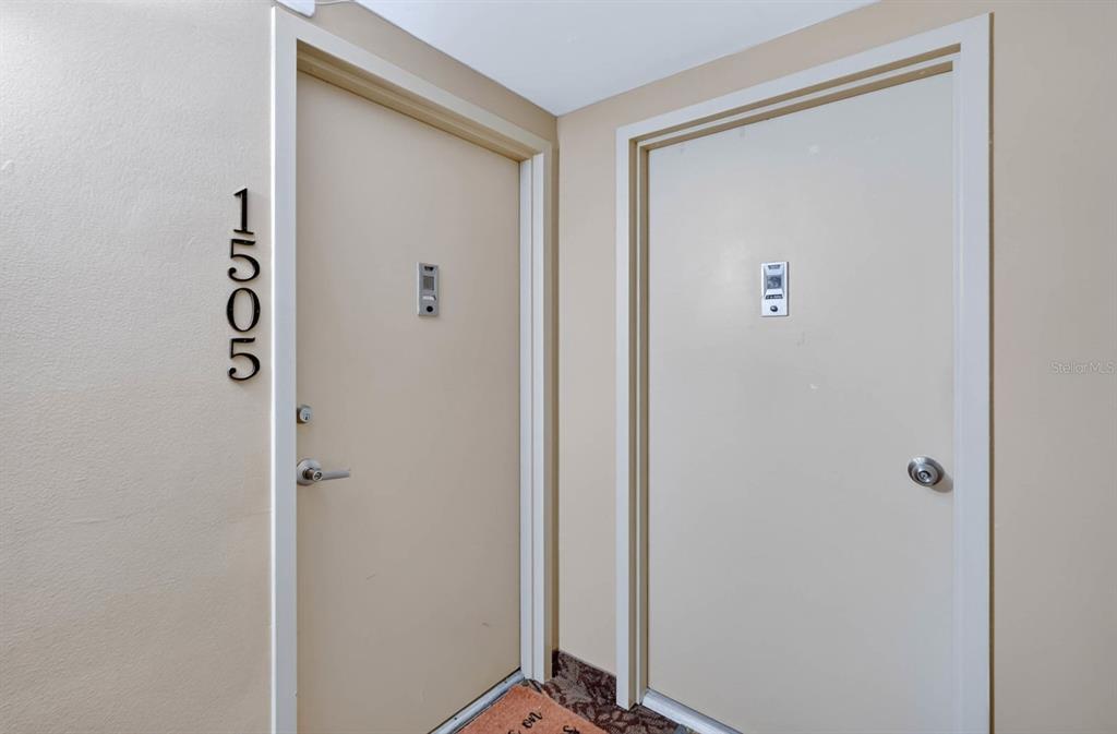 Two beige apartment doors are positioned side-by-side in a hallway with carpeted flooring — 2828 N ATLANTIC AVENUE UNIT 1505, DAYTONA BEACH, FL