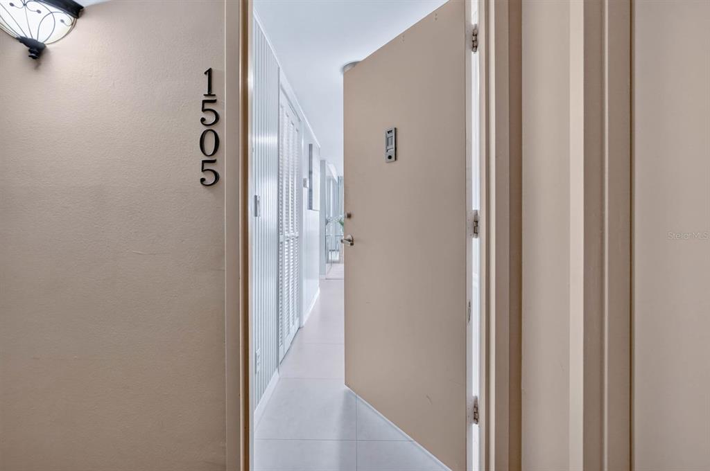An open door reveals a bright, tiled hallway with white walls and louvered closet doors — 2828 N ATLANTIC AVENUE UNIT 1505, DAYTONA BEACH, FL