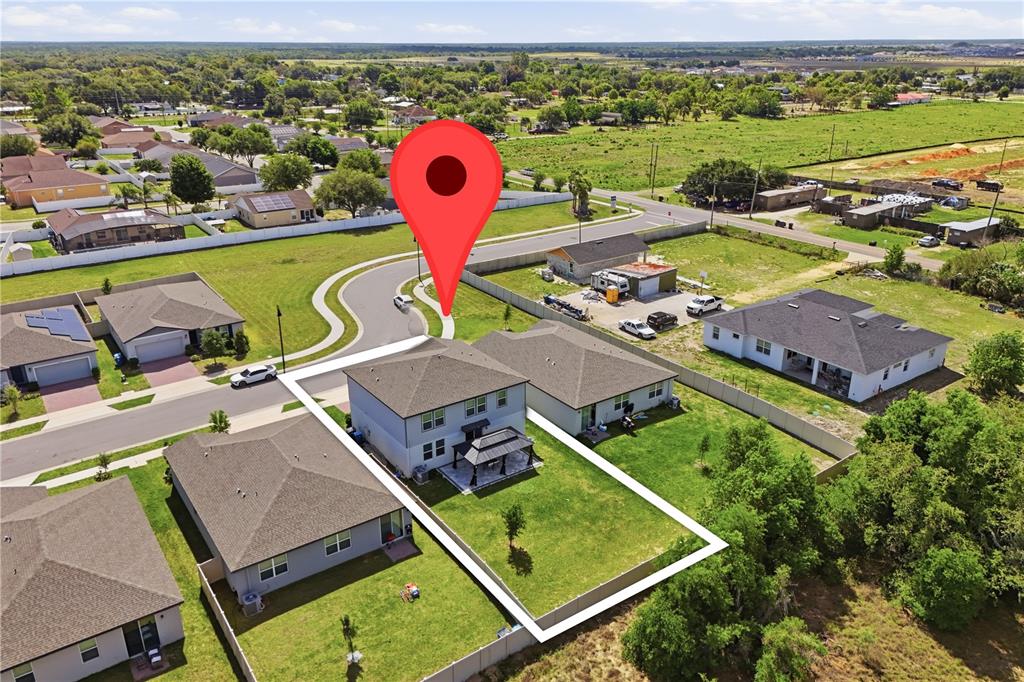 An aerial view shows a two-story house with a fenced backyard and a patio — 2424 WHITETAIL, DAVENPORT, FL