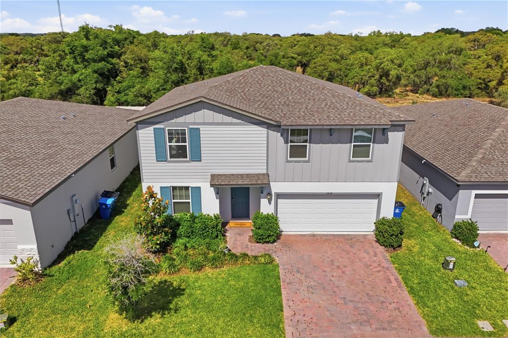 An aerial view of a two-story suburban house with a brick driveway and blue shutters — 2424 WHITETAIL, DAVENPORT, FL