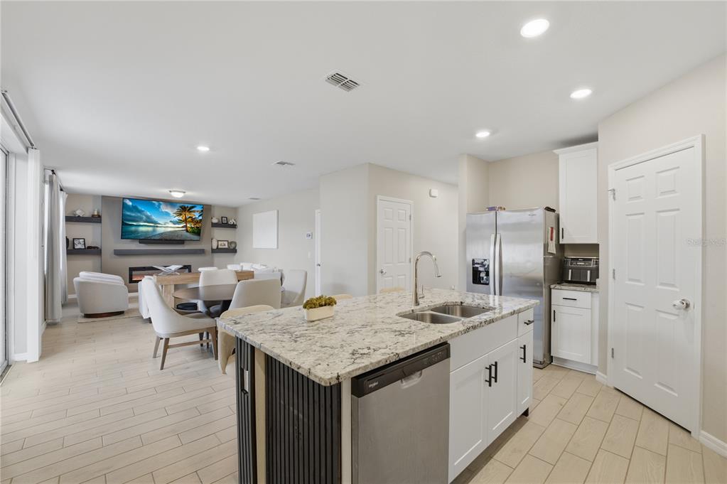 A kitchen island with a granite countertop sits in front of a dining and living area — 2424 WHITETAIL, DAVENPORT, FL