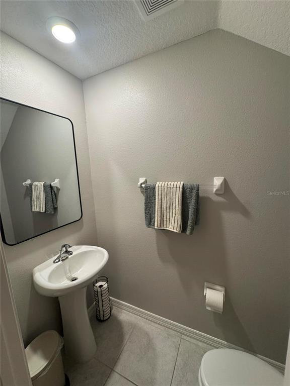 A small bathroom features a pedestal sink, a wall-mounted mirror, and a towel rack — 9640 PEMBROOKE PINES DRIVE, SUN CITY CENTER, FL