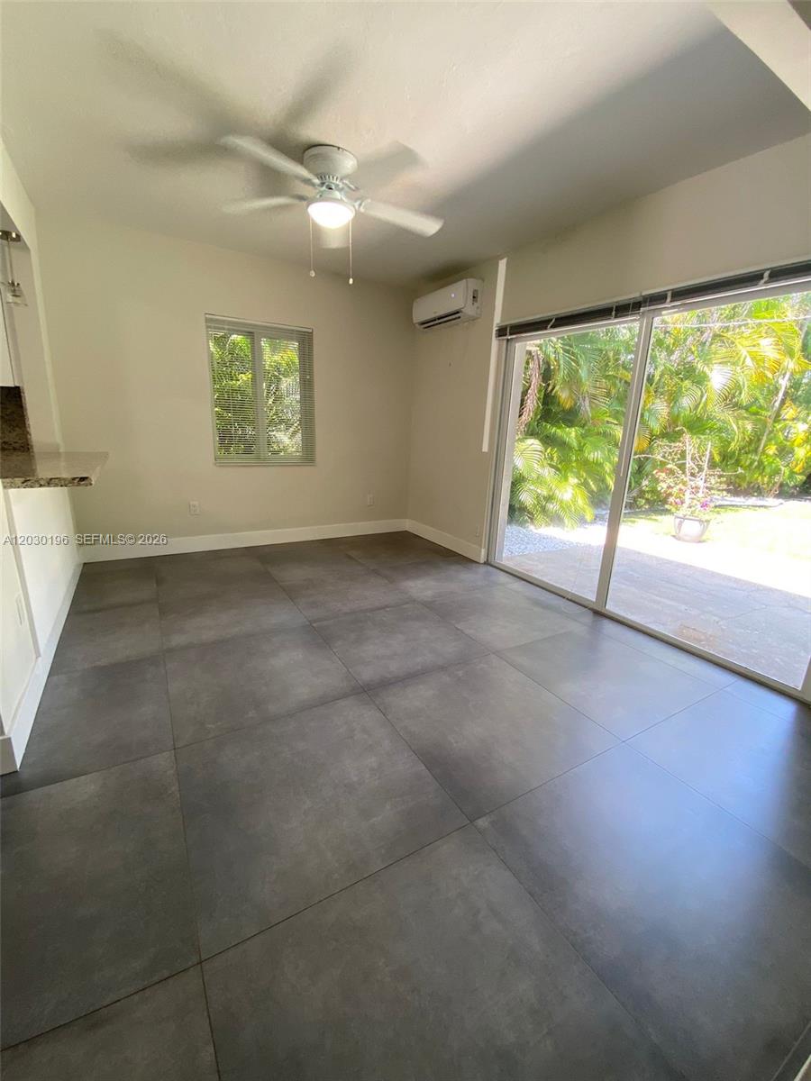 A room with large gray floor tiles, a ceiling fan, and a sliding glass door — 1511 NE 109th St, Miami FL 33161, MIAMI, FL