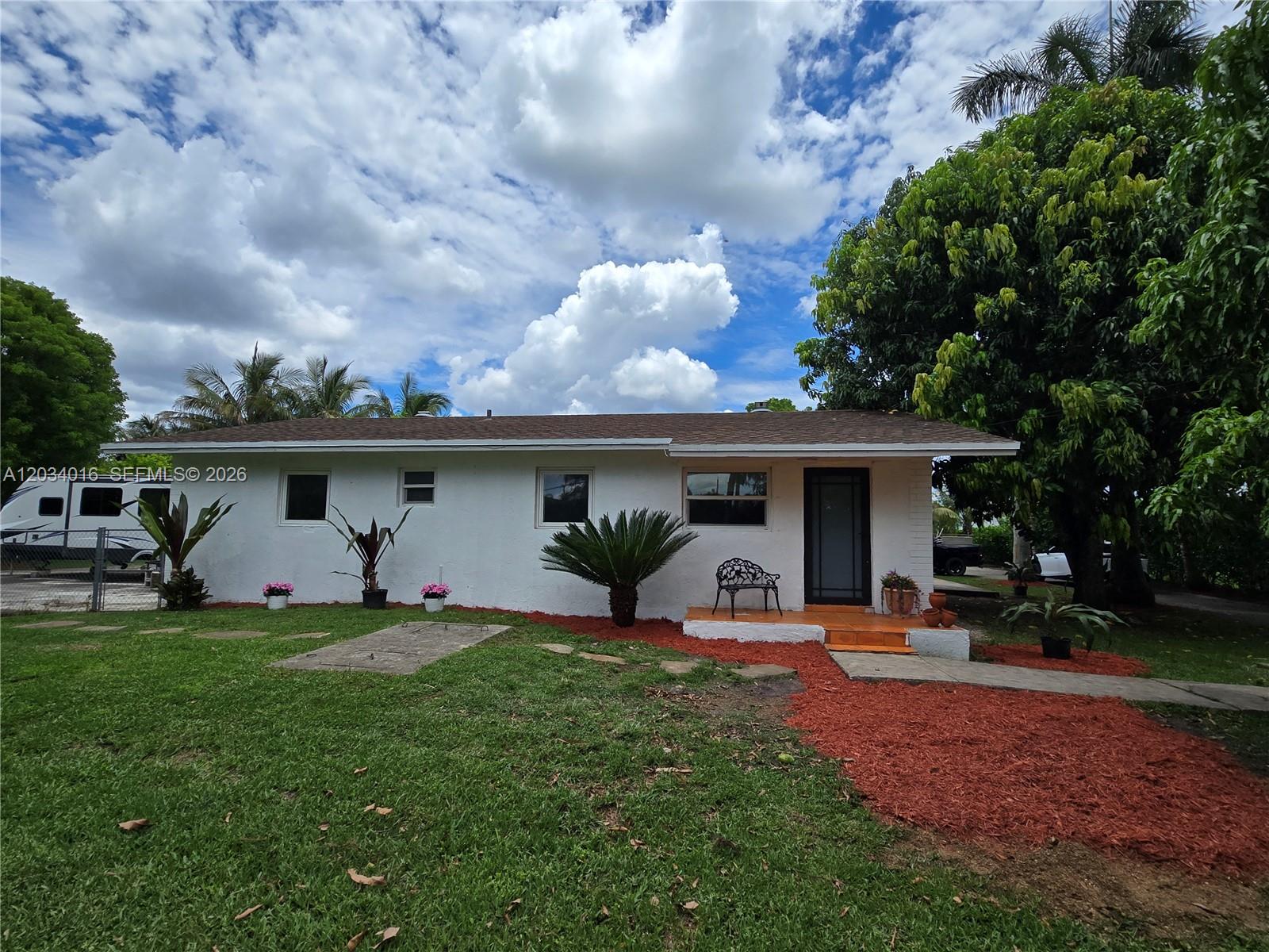 A white single-story house features a brown shingled roof, a front porch, and red mulch — 20595 SW 190th St, Miami FL 33187, MIAMI, FL