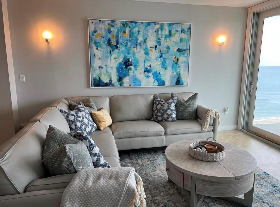 A living room features a grey sectional sofa, a round coffee table, and abstract wall art — 3450 S Ocean Boulevard # 610, Palm Beach FL 33480, PALM BEACH, FL
