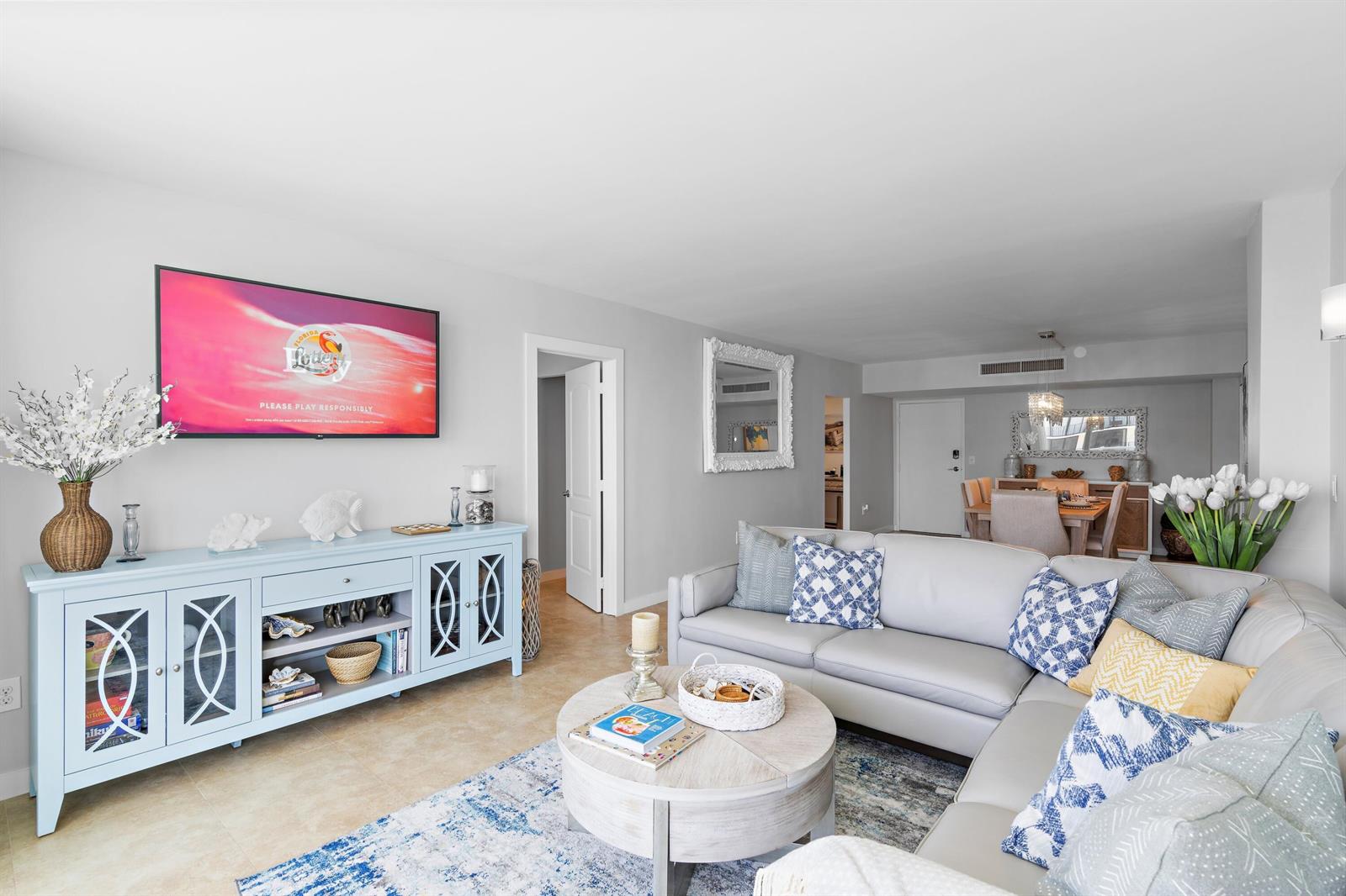 A living room features a light blue media console, a sectional sofa, and a dining area — 3450 S Ocean Boulevard # 610, Palm Beach FL 33480, PALM BEACH, FL