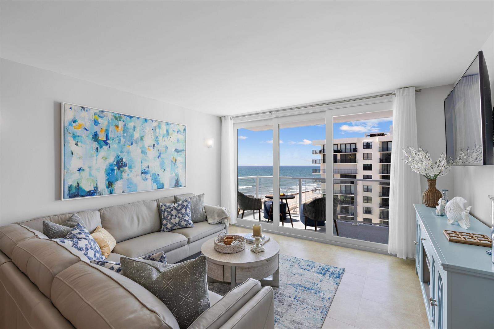 A living room features a sectional sofa, a round coffee table, and a balcony overlooking the ocean — 3450 S Ocean Boulevard # 610, Palm Beach FL 33480, PALM BEACH, FL