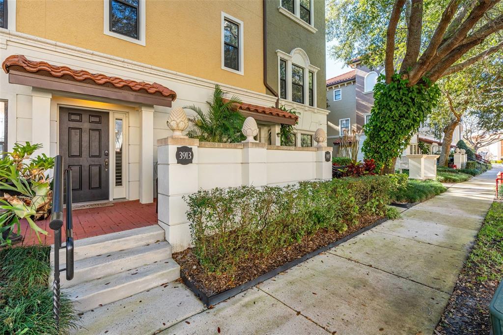 A multi-story townhouse exterior features a brick entryway, a low wall, and a sidewalk — 3913 MESSINA DRIVE, LAKE MARY, FL