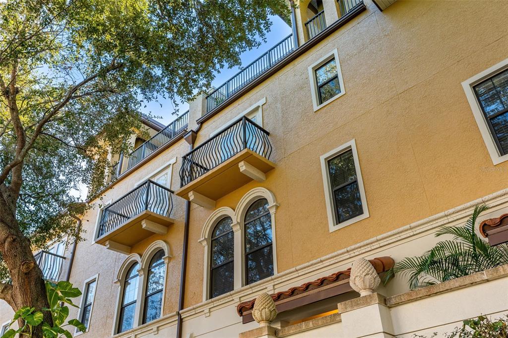 A low-angle view of a multi-story yellow stucco building with balconies and arched windows — 3913 MESSINA DRIVE, LAKE MARY, FL