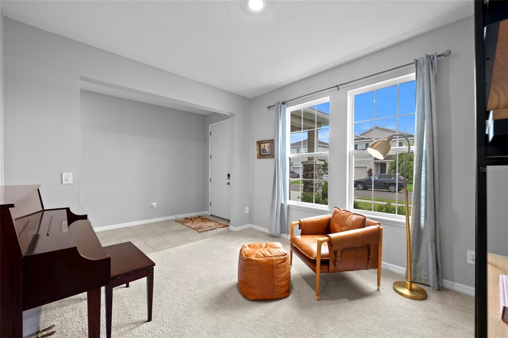 A living room features a piano, a leather armchair with ottoman, and two large windows — 2136 MIDNIGHT PEARL DRIVE, SARASOTA, FL
