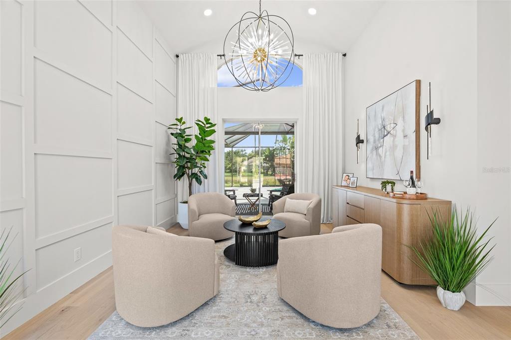 A bright living room features four beige armchairs, a round coffee table, and tall windows — 7318 EATON COURT, UNIVERSITY PARK, FL