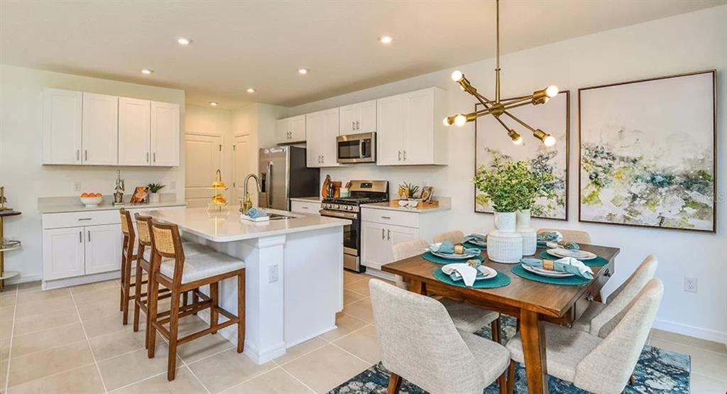 A kitchen and dining area featuring white cabinets, a center island, and a wooden table — 13819 SHELLMORE AVENUE, PALMETTO, FL