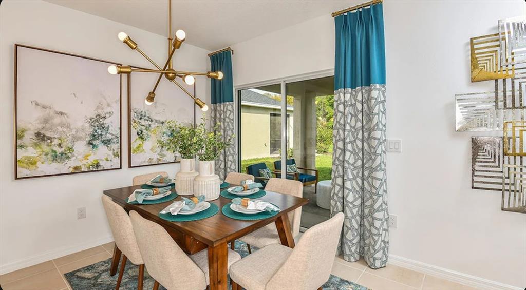 A dining room features a wooden table, modern chandelier, abstract wall art, and sliding glass doors — 13819 SHELLMORE AVENUE, PALMETTO, FL