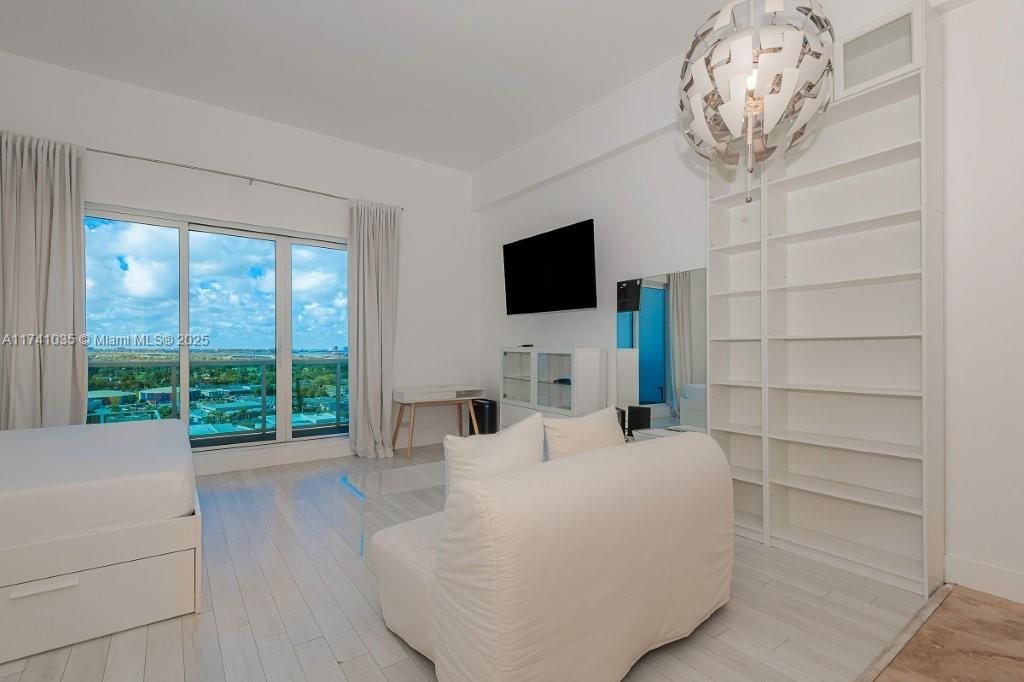A bedroom features white tile floors, a tall shelving unit, and a view of water — 2301 Collins Ave # 1629, Miami Beach FL 33139, MIAMI BEACH, FL