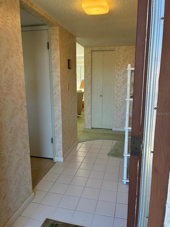 A tiled entryway leads to a hallway with wallpaper, a closet, and carpeted living space — 7020 COGNAC DRIVE UNIT 4, NEW PORT RICHEY, FL