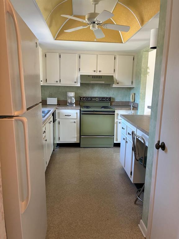 A kitchen features white cabinets, a green stove, a ceiling fan, and light-colored flooring — 7020 COGNAC DRIVE UNIT 4, NEW PORT RICHEY, FL