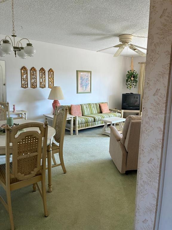 A living and dining area features green carpet, a striped sofa, and a chandelier — 7020 COGNAC DRIVE UNIT 4, NEW PORT RICHEY, FL