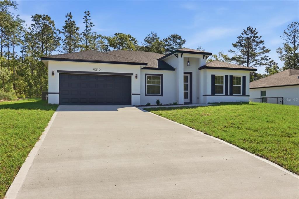 A modern single-story house with a white exterior, dark trim, and a two-car garage — 9319 N CORTLANDT DRIVE, CITRUS SPRINGS, FL