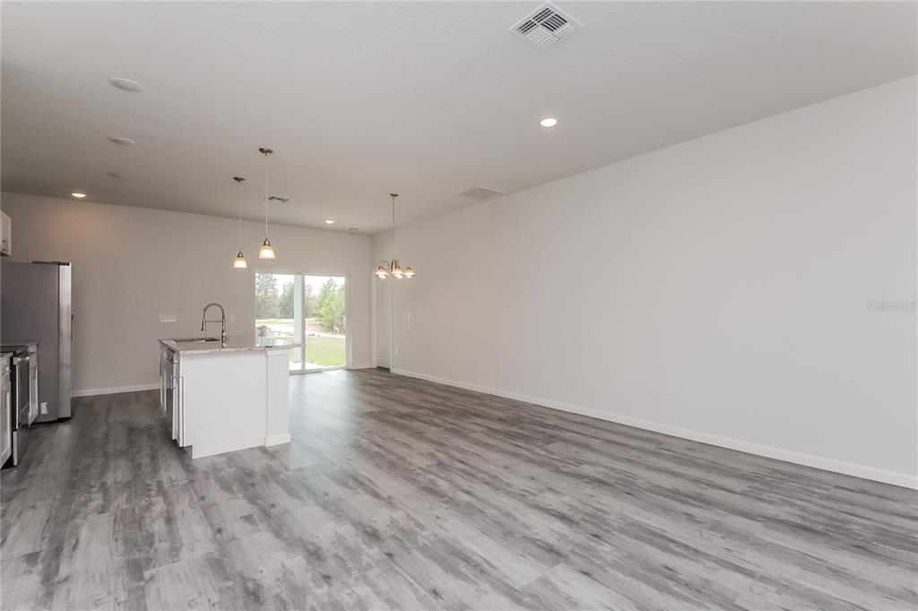 A kitchen with a white island and stainless steel appliances opens into a large living area — 137 VIOLET CT, KISSIMMEE, FL