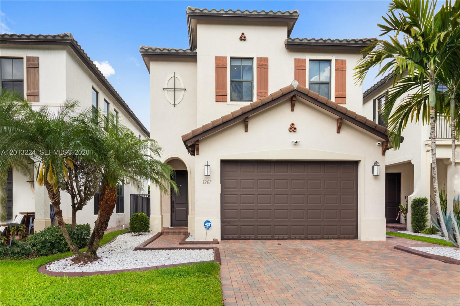 A two-story stucco house features a brown garage door, tiled roof, and a palm tree — 3261 W 99th Pl, Hialeah FL 33018, HIALEAH, FL