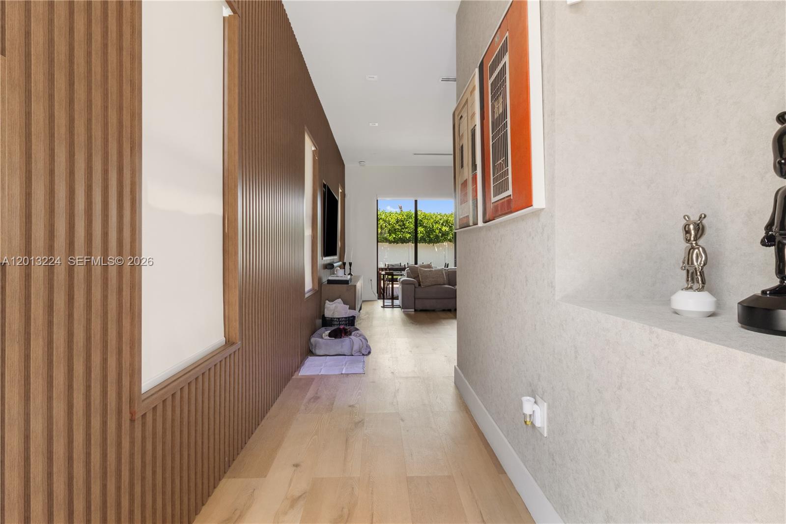A hallway with wood-slatted walls leads toward a living area with a view of greenery — 3261 W 99th Pl, Hialeah FL 33018, HIALEAH, FL