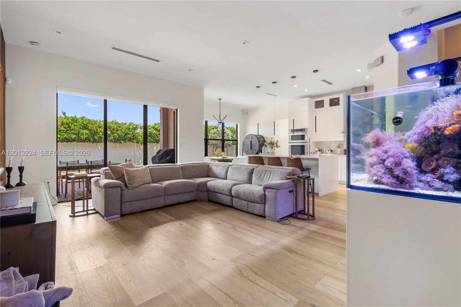 A modern open-concept living room features a large gray sectional sofa and a saltwater aquarium — 3261 W 99th Pl, Hialeah FL 33018, HIALEAH, FL