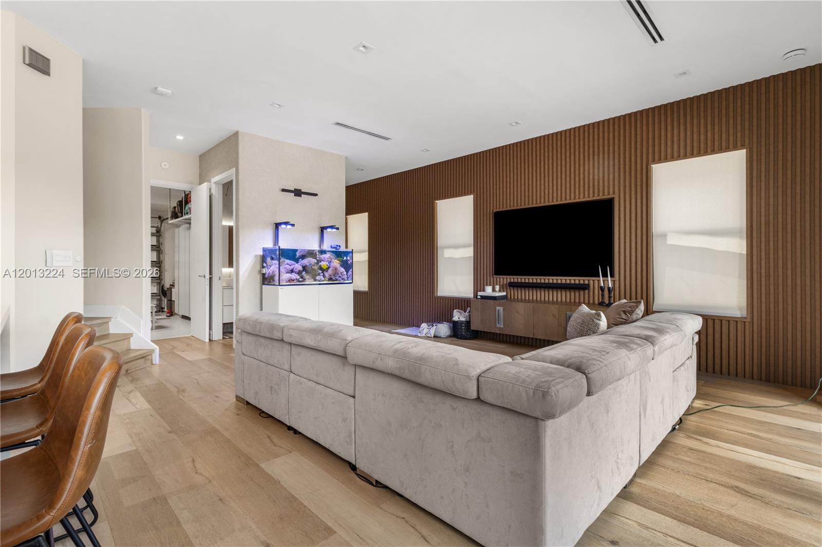 A living room features a large sectional sofa, a wall-mounted television, and wood-slatted paneling — 3261 W 99th Pl, Hialeah FL 33018, HIALEAH, FL