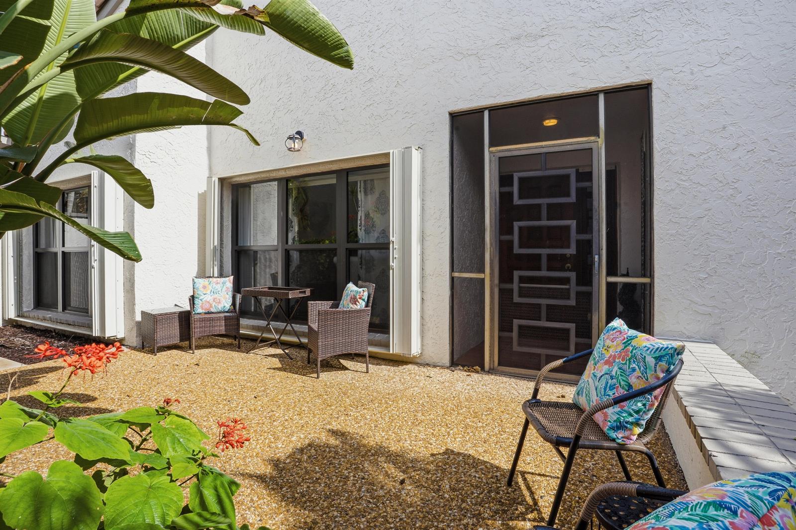 A gravel patio features outdoor furniture, a screen door, and a large potted plant — 11810 Kiva Drive, Boynton Beach FL 33437, BOYNTON BEACH, FL