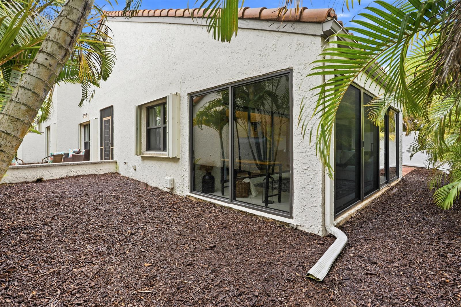 The exterior of a white stucco house features a screened patio and mulch landscaping — 11810 Kiva Drive, Boynton Beach FL 33437, BOYNTON BEACH, FL