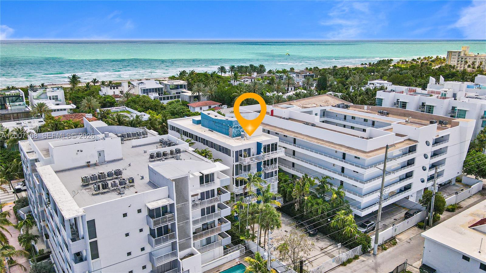An aerial view shows a multi-story white apartment building near a beach and ocean — 7824 Collins Ave # 401, Miami Beach FL 33141, MIAMI BEACH, FL