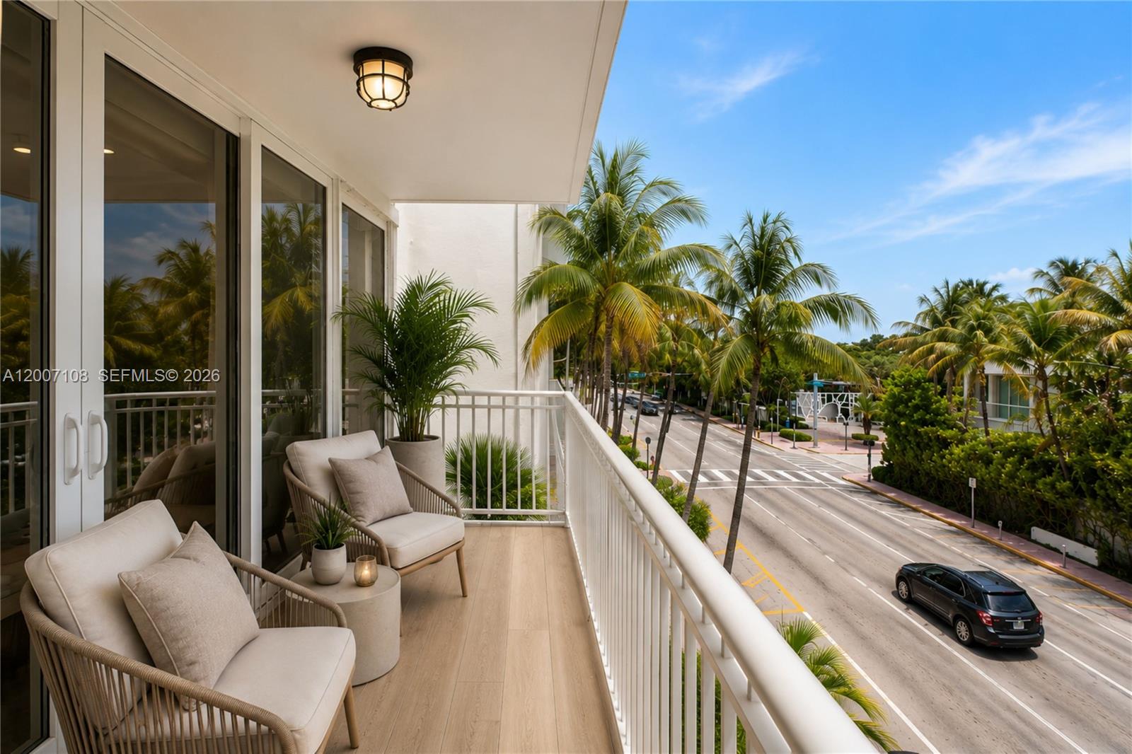 A balcony with two chairs, a small table, and a view of a street — 7824 Collins Ave # 401, Miami Beach FL 33141, MIAMI BEACH, FL