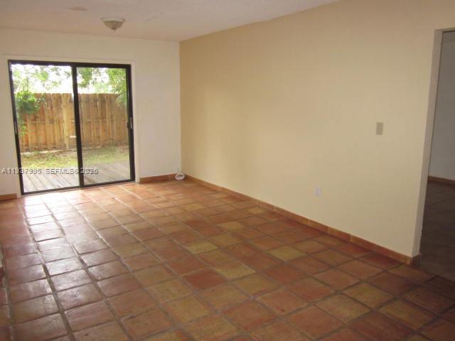 An empty room with terracotta tile flooring and a sliding glass door leading outside — 13224 SW 10 TE, Miami FL 33184, MIAMI, FL