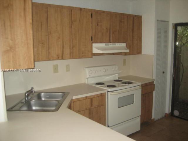 A kitchen features light wood cabinets, white countertops, a double sink, and a white stove — 13224 SW 10 TE, Miami FL 33184, MIAMI, FL