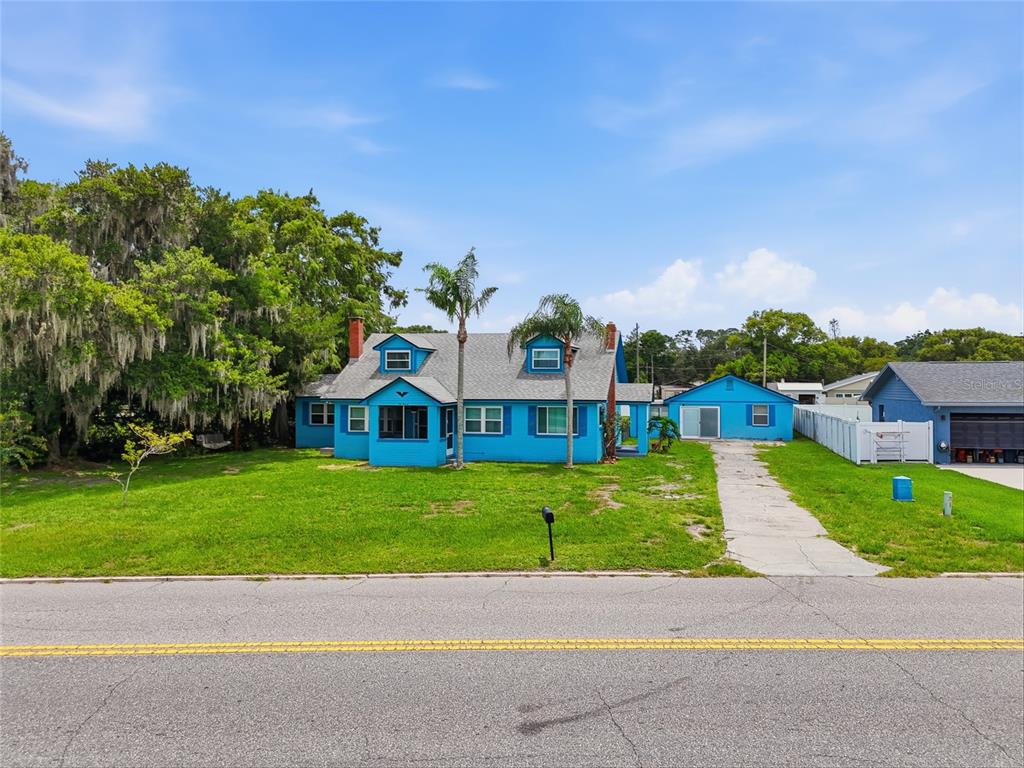 A bright blue house with a detached garage sits behind a lawn and paved driveway — 211 LAKESHORE BOULEVARD, ST CLOUD, FL
