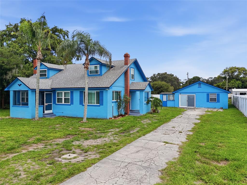 A bright blue two-story house with a detached garage and a cracked concrete driveway — 211 LAKESHORE BOULEVARD, ST CLOUD, FL