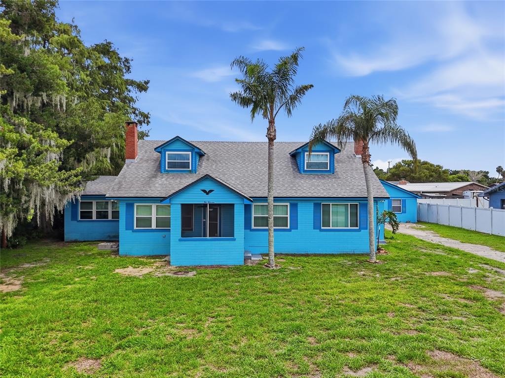 A bright blue, single-story house with two dormer windows and two palm trees in front — 211 LAKESHORE BOULEVARD, ST CLOUD, FL