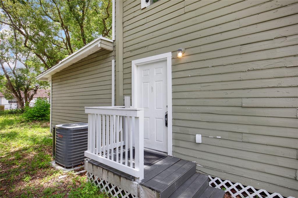 An exterior view of a house with olive green siding, a white door, and wooden steps — 2508 YALE AVENUE, SANFORD, FL