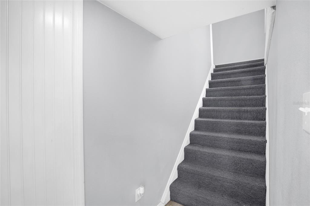 A staircase with dark gray carpeting leads upward between light gray walls — 2508 YALE AVENUE, SANFORD, FL