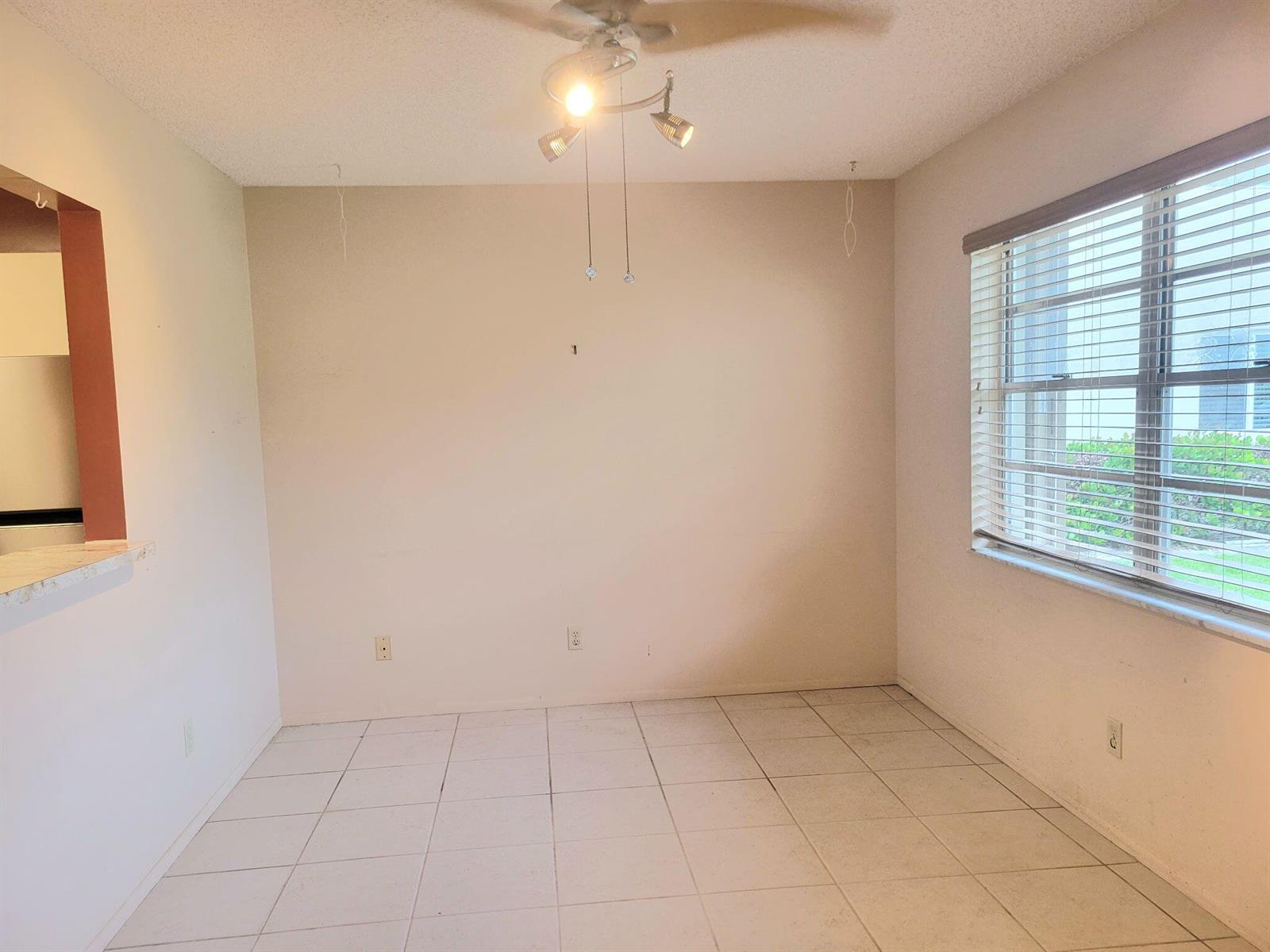 An empty dining area features light-colored tile flooring, beige walls, and a ceiling light fixture — 26 Lake Vista Trail # 104, FL 34952, FL
