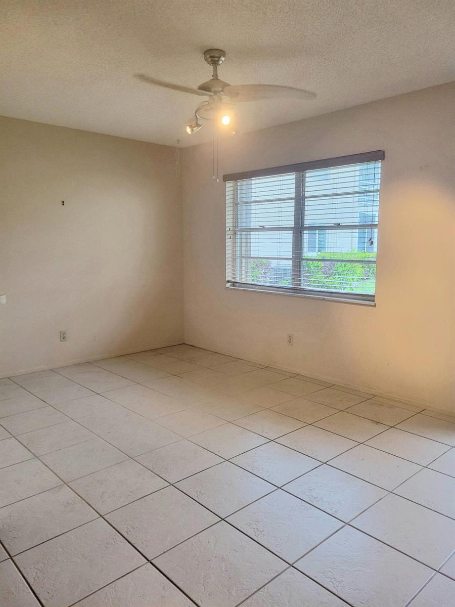 An empty room with white tile flooring, a ceiling fan, and a window with blinds — 26 Lake Vista Trail # 104, FL 34952, FL