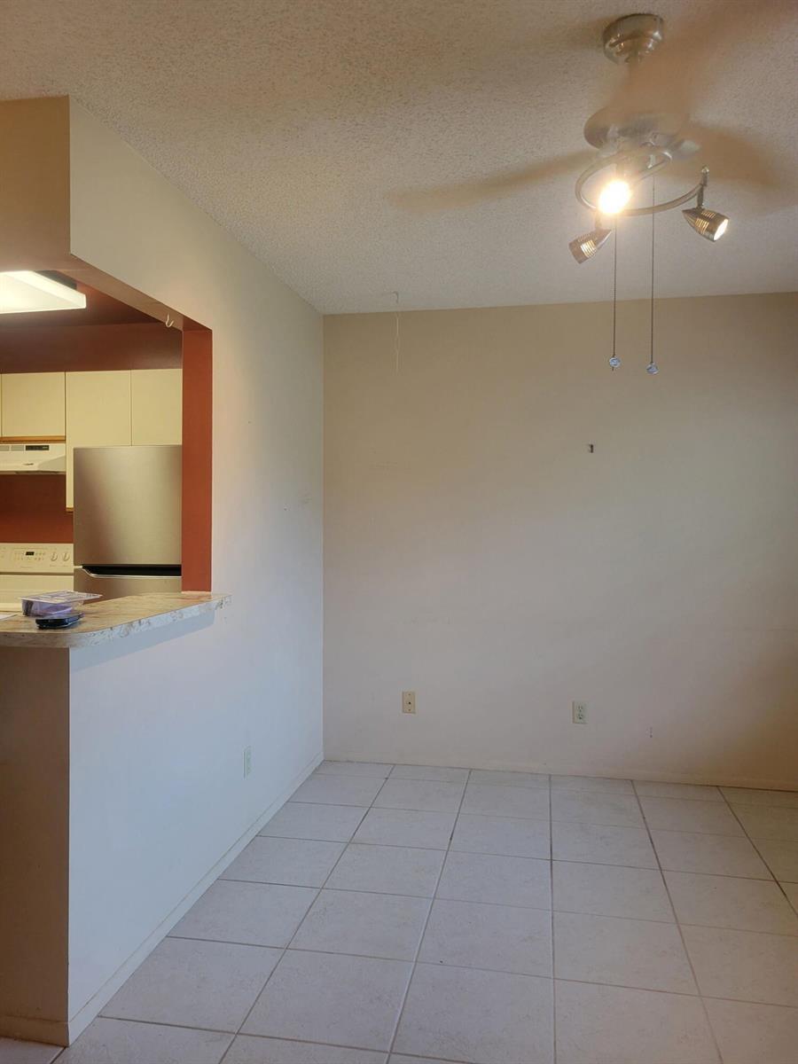 An empty dining area with tile flooring, a ceiling light fixture, and a kitchen pass-through — 26 Lake Vista Trail # 104, FL 34952, FL