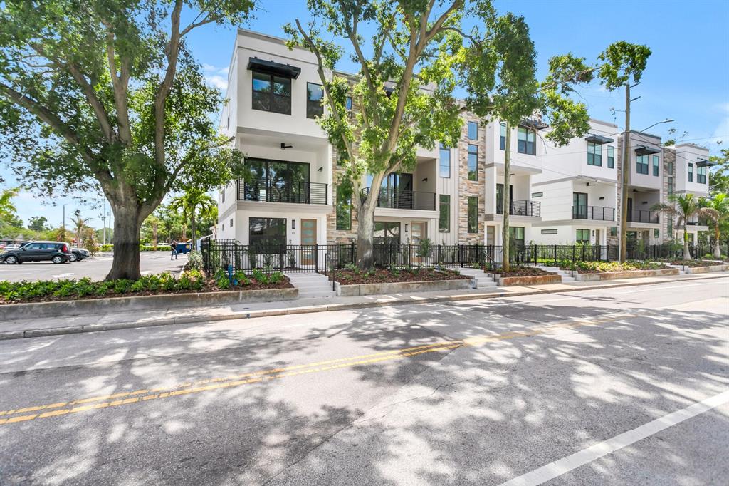 A row of modern three-story townhomes with stone accents, balconies, and black metal fencing — 50 64TH STREET S, ST PETERSBURG, FL