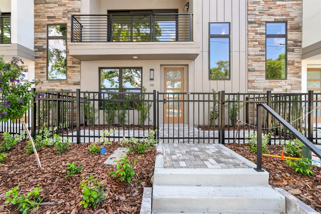 The exterior of a modern townhouse features a stone facade, a balcony, and a gated entrance — 50 64TH STREET S, ST PETERSBURG, FL