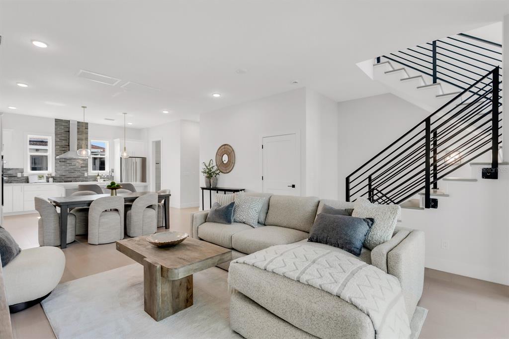 A modern living room features a sectional sofa, a wooden coffee table, and a staircase — 50 64TH STREET S, ST PETERSBURG, FL