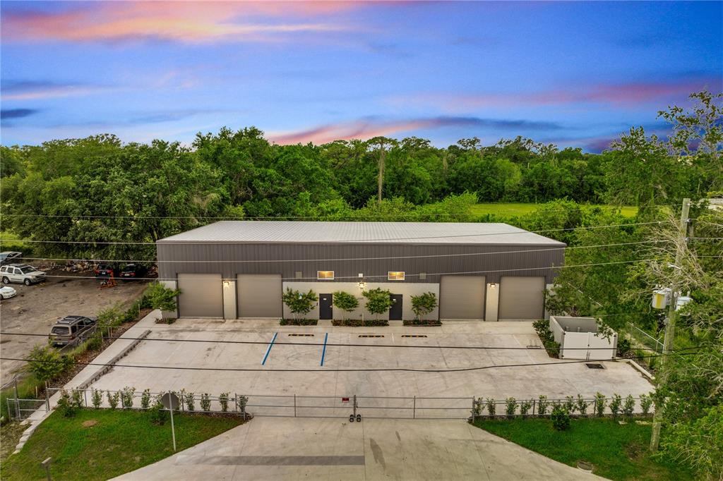 An aerial view shows a modern industrial building with four garage doors and a paved lot — 560 BARRY STREET, ORLANDO, FL