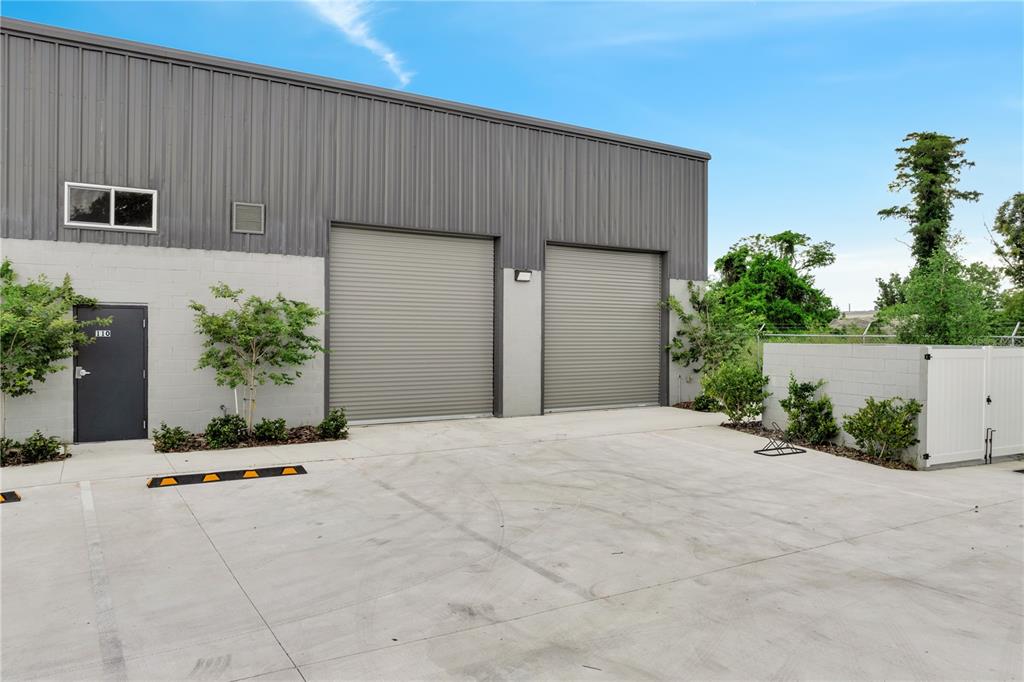 An exterior view of a commercial warehouse building with two roll-up doors and a pedestrian entrance — 560 BARRY STREET, ORLANDO, FL